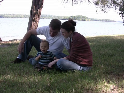 一个年轻的家庭坐在PAL湖边视频下载