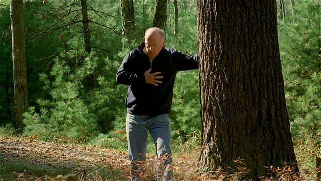 用平底锅拍老人在树林里远足/靠在树上，抓着胸口/使用吸入器视频下载