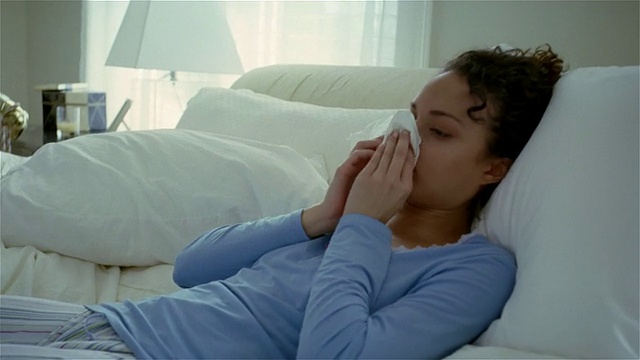中镜头生病的女人躺在床上，站起来擤鼻涕/索尔伯里，宾夕法尼亚州视频下载