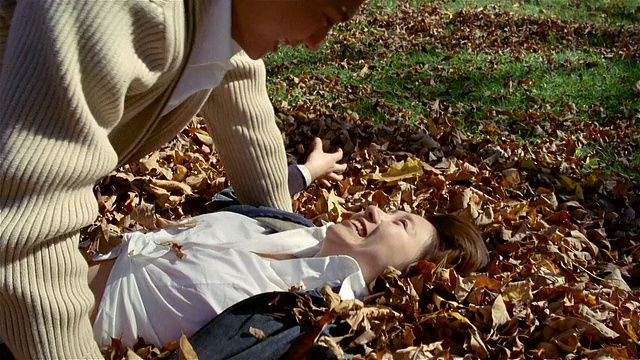 一对年轻夫妇在秋叶草上嬉笑打闹视频素材