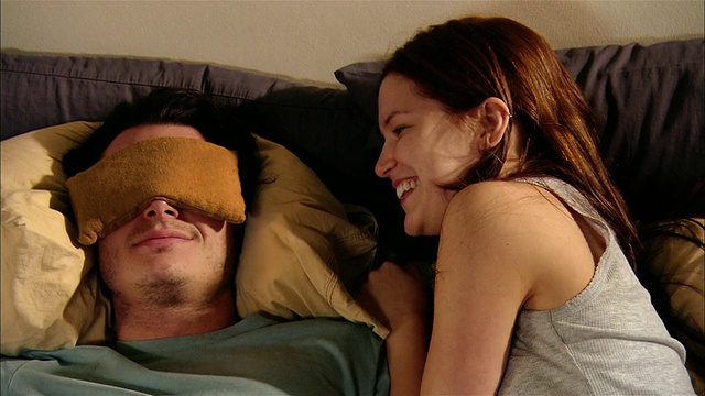 女人躺在床上看杂志，旁边的男人戴着眼枕视频下载