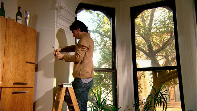 中等拍摄的人在梯子上测量模具的窗户/布鲁克林，纽约视频下载