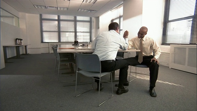 多莉走进会议室，两个男人在桌子上扳手腕/男人作弊和站起来假装胜利视频素材