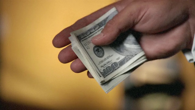 折叠的100美元钞票在两名男子之间交换双手的特写视频下载