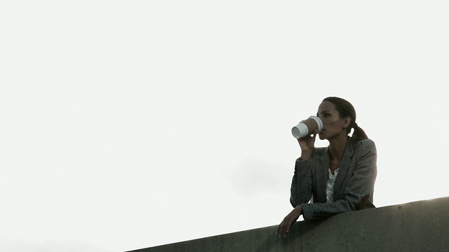 女商人在墙边用一次性杯子喝东西，角度低视频素材