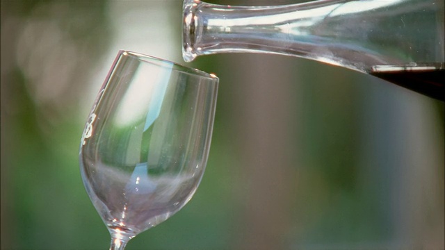 特写的空酒杯/红酒被倒入玻璃杯从玻璃瓶视频素材