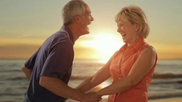 在夕阳和大海的背景下，老夫妇在海滩上拥抱视频下载