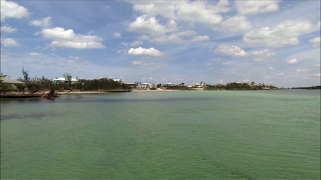 宽阔的镜头，在海滩海湾广阔的水域与度假村的背景/平移到海上的船只视频下载