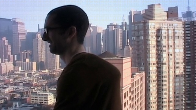 中景:一个年轻人站在阳台上，手臂伸开并旋转，展示了他的柔韧性，背景是纽约市视频下载
