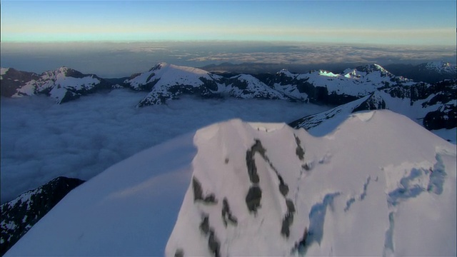 在新西兰峡湾国家公园云线上方的雪山山脊上的空中飞行视频下载