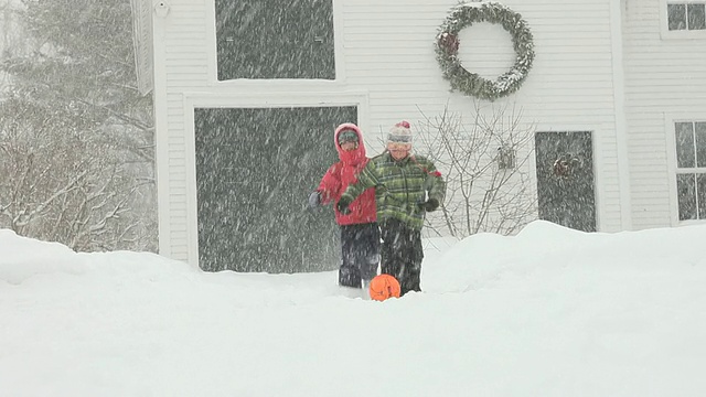 在暴风雪期间男孩和女孩踢足球/雅茅斯，缅因州，美国视频下载
