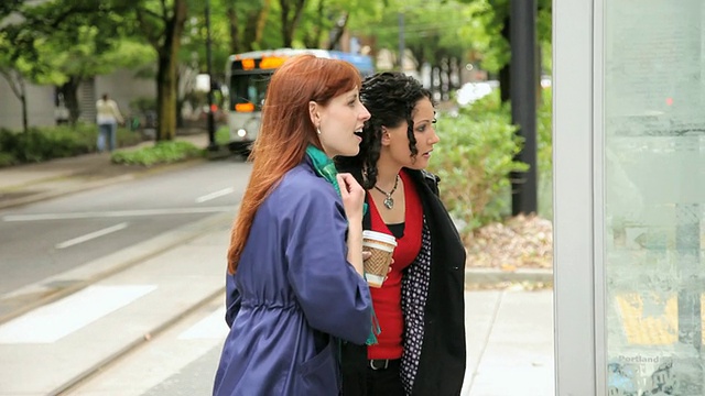 美国俄勒冈州波特兰市，两名女子在查看公交车时刻表，并在经过一辆公交车后奔跑视频素材