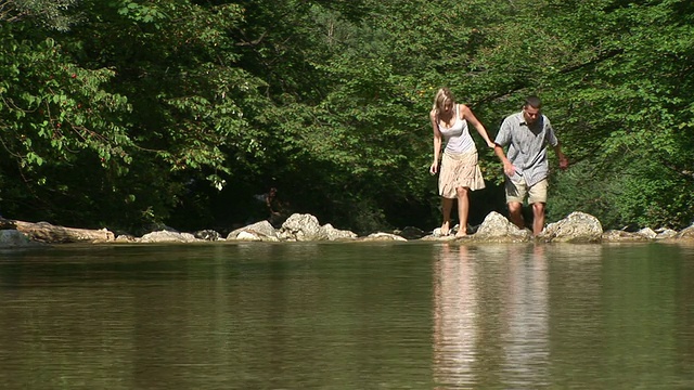 一对夫妇站在湖边的岩石上视频素材