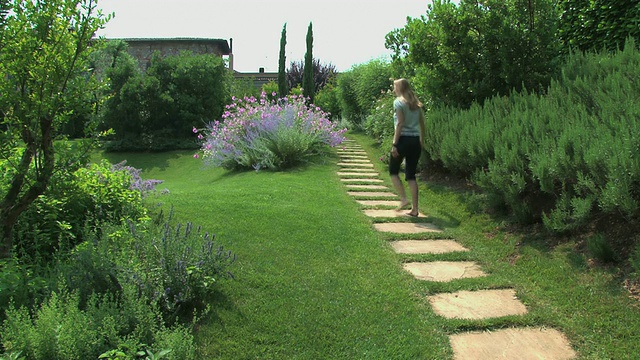金发女人走在美丽的托斯卡纳花圃里视频下载