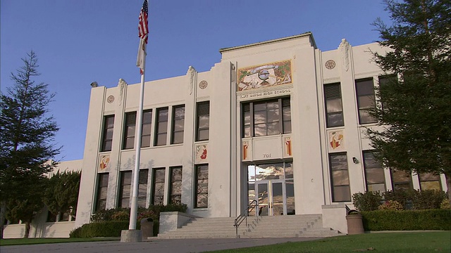 美国加州贝克斯菲尔德的塔夫脱联合高中，门上有一幅科学和教育壁画，还有一根旗杆视频素材