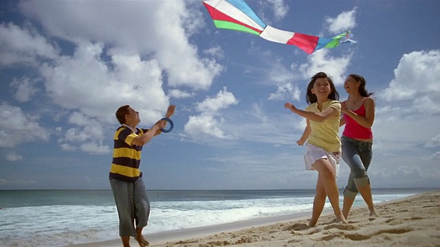 一名男子和两名女子在印尼巴厘岛的海滩上放风筝视频素材