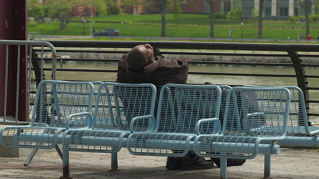 一个流浪汉睡在长椅上。视频素材