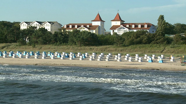 德国梅克伦堡西波美拉尼亚，波罗的海/辛诺维茨海滩上带有建筑背景的WS带帽沙滩椅视频素材