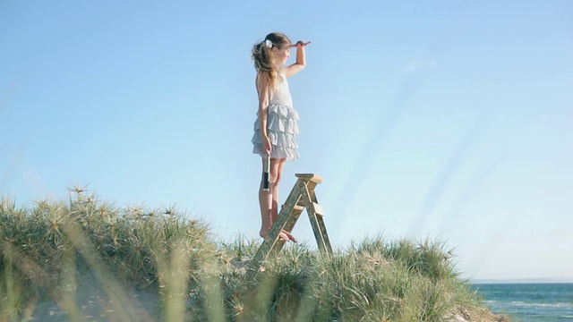 在澳大利亚维多利亚州的墨尔本海滩，站在梯子上的女孩通过望远镜看视频下载