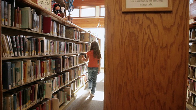 在美国亚利桑那州弗拉格斯塔夫图书馆的书架上挑书的女孩视频素材