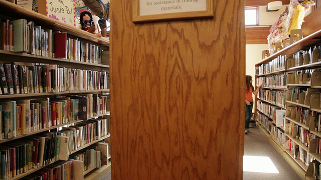 美国亚利桑那州弗拉格斯塔夫图书馆的WS女孩在书架之间行走视频素材