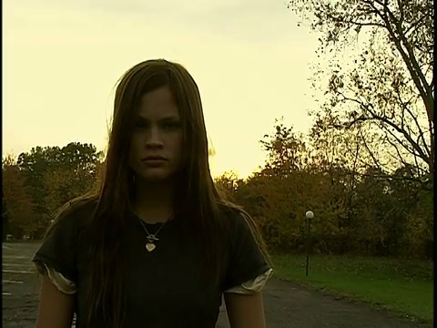 日落时分，年轻女子戴着项链站在公园里视频下载