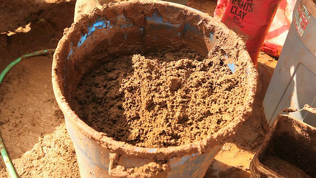 cutu TD Carpenter在手工搅拌土坯泥之前添加粘土和水，这是美国密歇根州草地湖的一个节能柱子视频下载