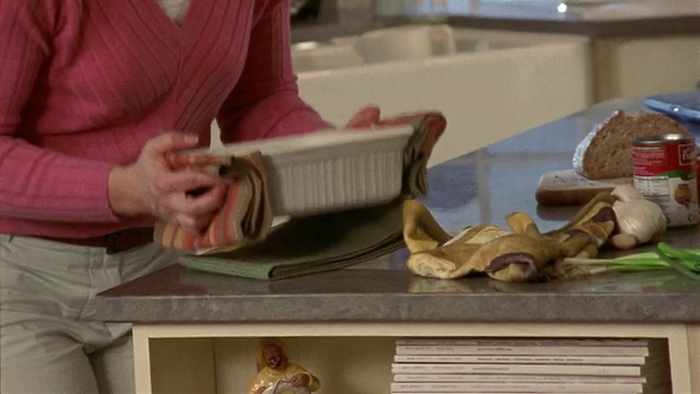 中镜头-特写女人在厨房的桌子上提供砂锅晚餐视频素材