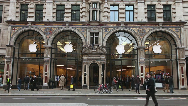 英国大伦敦摄政街的苹果商店，公交车在行驶，人们在微风中挥舞着苹果旗视频素材