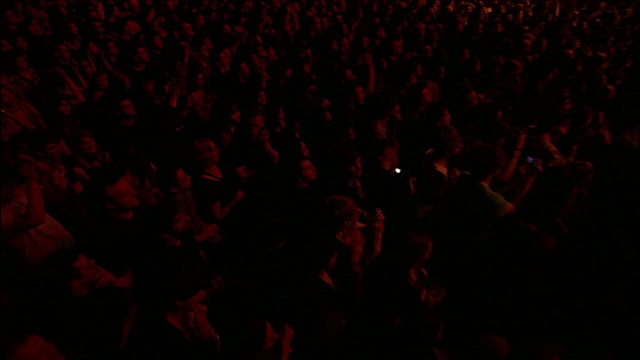 在英国伦敦，一场大型音乐会上，一群观众在红色灯光下欢呼视频素材