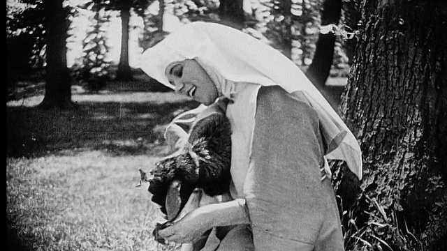 1916年B/W中拍摄一名年轻的修女在花园里拥抱和喂养山羊视频素材