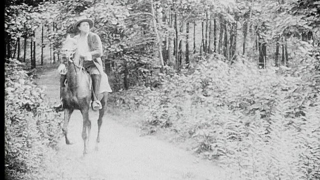 1916 B/W蒙太奇宽镜头-特写年轻的修女抱着鸟在花园里/教堂的钟声左右响/男人骑在马背上在树林小径上视频素材