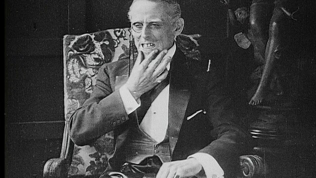 1916年B/W中镜头诡计多疑的男爵在扶手椅中紧握双手视频素材