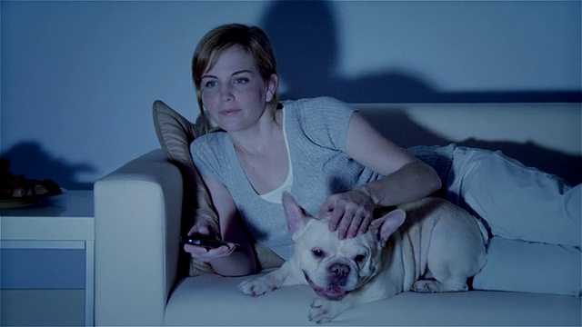 MS，年轻的女人和狗躺在沙发上，看电视视频下载