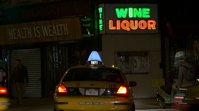 夜间交通驶过一个酒和酒的霓虹灯招牌。霓虹灯在闪烁视频素材
