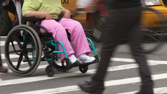 一个男人推着一个坐轮椅的女人穿过街道视频素材