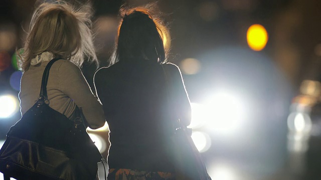 晚上，两个穿剪影的女人在等出租汽车视频素材