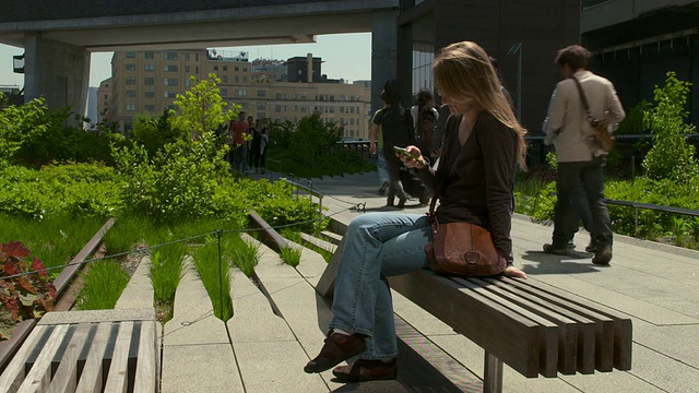坐在纽约高架公园长椅上的女人们在用手机发短信。视频素材