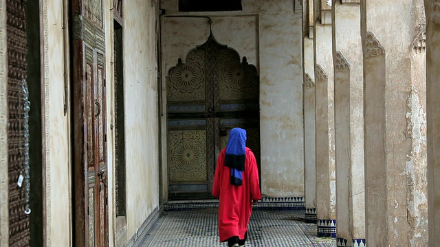 非洲摩洛哥，穿着传统服饰的男子走在美丽华丽的古老非斯宫殿里视频下载