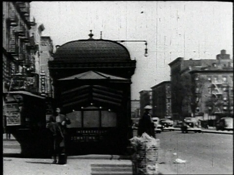 1940年，一名妇女从地铁走到哈莱姆区的人行道上，看小册子，城市街道，许多行人/纽约市视频下载