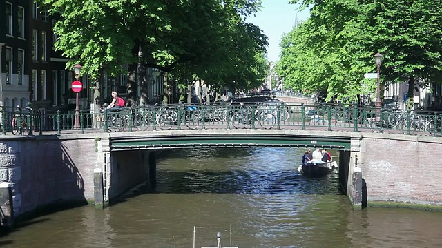 在荷兰阿姆斯特丹，自行车停在桥附近时骑自行车的景象视频素材