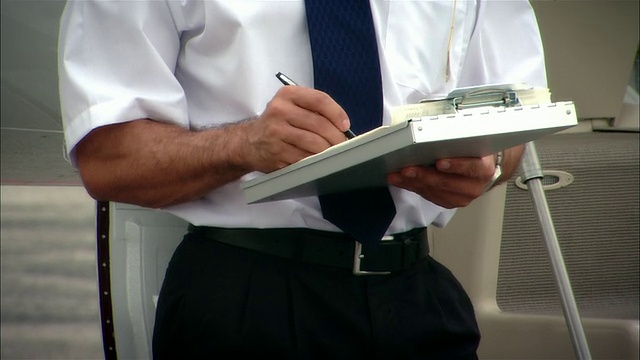 在美国佛罗里达州迈阿密的奥帕洛卡机场，飞行员在私人飞机旁的剪贴板上写特写视频下载