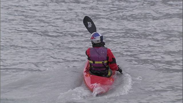 中等轨迹右-美国阿拉斯加，一名皮划艇运动员滑下冰川，进入冰冷的水域视频素材