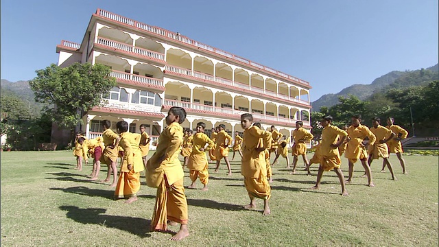一群穿着橙色长袍的男孩一起伸展/印度视频素材