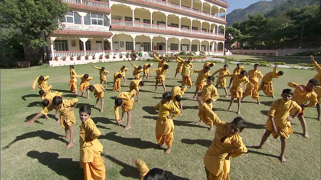 一群穿着橙色长袍的男孩跟随教练/印度一起伸展视频素材