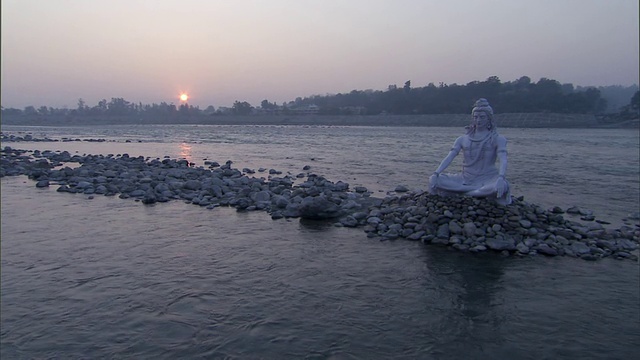 WS TU TD日落时河流中岩石堆中的白色宗教雕像/印度视频下载