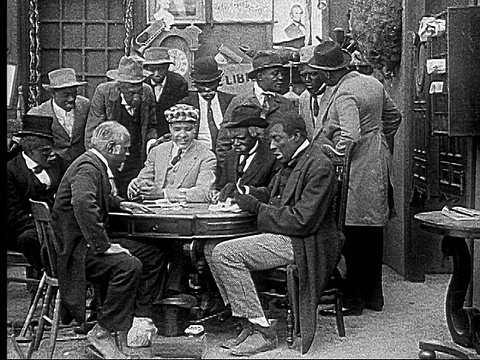 1916 B&W电影蒙太奇MS男人把牌放在脚趾之间传递到桌子下打牌/男人拿着牌并环顾四周视频素材
