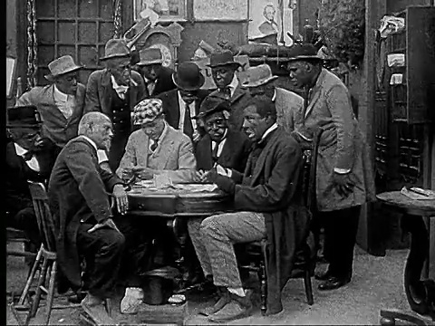 1916 B&W电影蒙太奇MS男人把牌放在脚趾之间传递到桌子下打牌/男人拿着牌并环顾四周视频素材