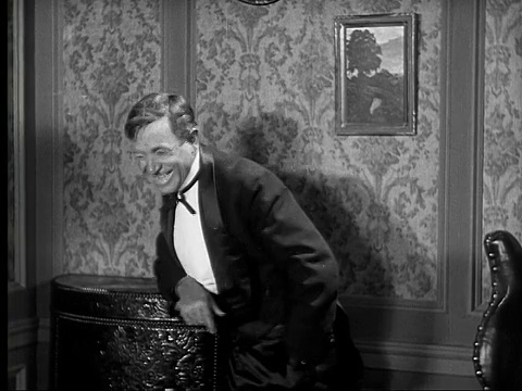 1924 B&W电影蒙太奇MS男人穿着燕尾服大笑/女人说话和看起来渴望与严肃的巴特勒在背景视频下载
