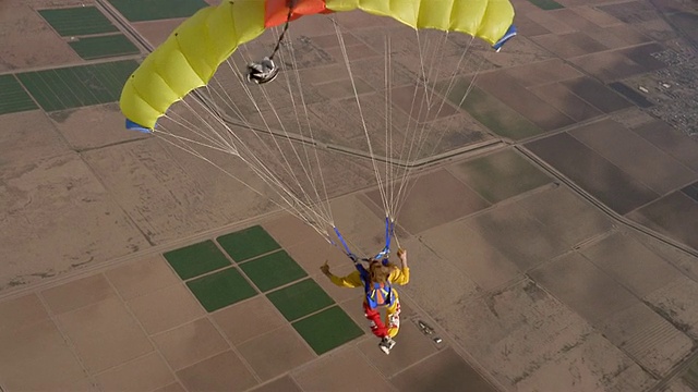 WS人跳伞和漂浮在半空中的大黄色降落伞上方拼凑景观/埃洛伊，亚利桑那州，美国视频素材